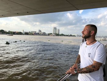 Man looking at view while standing by river in city