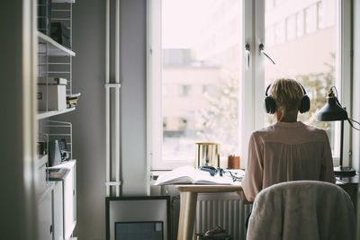 Rear view of woman in office at home sitting at desk