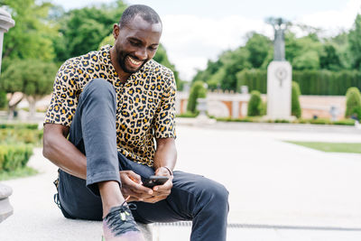 Positive afro american stylish man in european city with electronic device