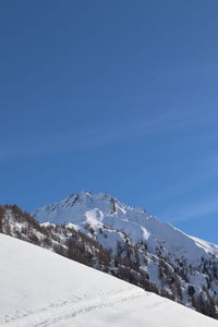 Snow covered mountain against blue sky