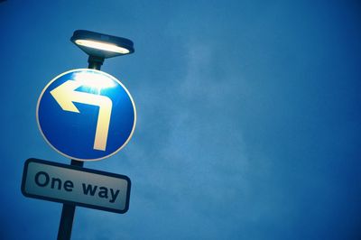 Low angle view of road sign against blue sky