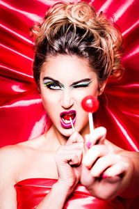 Portrait of beautiful young woman holding while eating lollipop