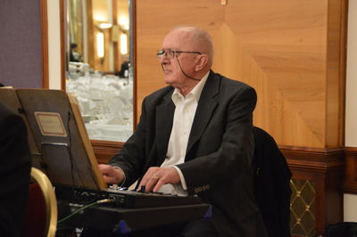 Senior man playing electric piano at event