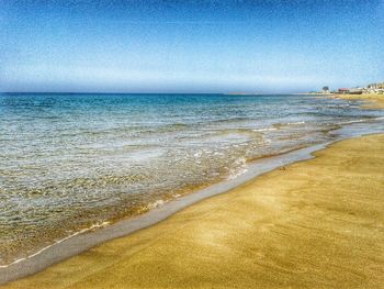 Scenic view of beach against clear blue sky