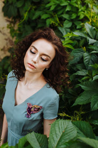 Young woman wearing make-up while standing against plants