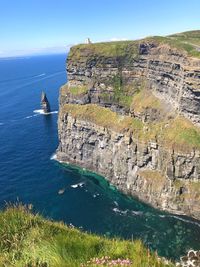 Scenic view of sea by cliff against sky