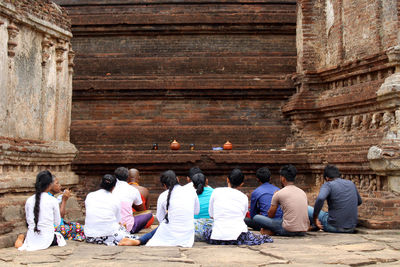Rear view of people sitting outside temple