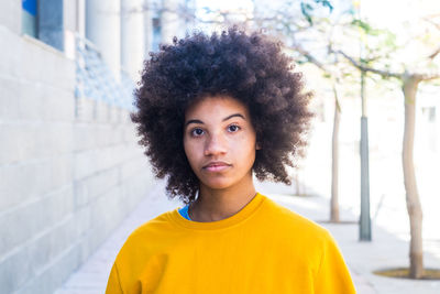 Portrait of beautiful young woman standing against yellow wall