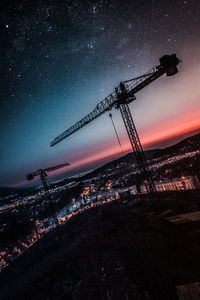 Low angle view of silhouette cranes against sky at night