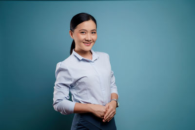Portrait of a smiling young woman against blue background