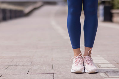 Low section of woman standing on footpath