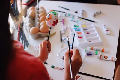 Cropped image of girl painting eggshell at table