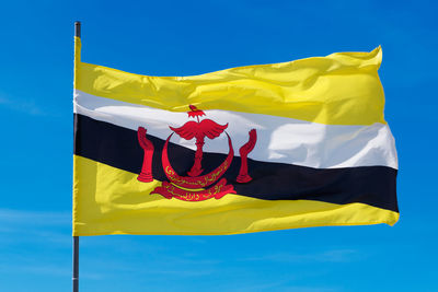 Low angle view of flags flag against blue sky