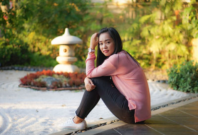 Portrait of young woman sitting on footpath