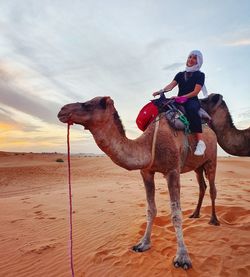 Woman riding camel on sand