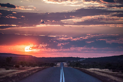 Empty road against sky during sunset