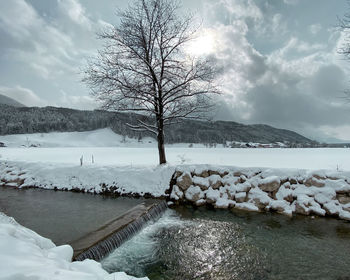 Scenic view of frozen river by snowcapped mountains against sky