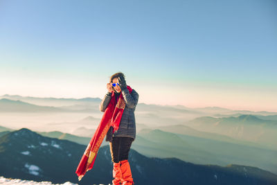 Man standing against mountain range against clear sky