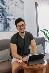 Portrait of young man using laptop while sitting on sofa at home