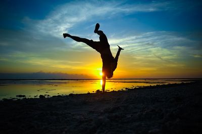 Full length of a silhouette man jumping on beach