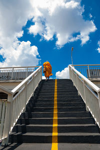 Low angle view of monk moving up on steps against sky