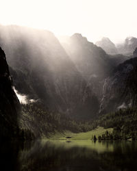 Scenic view of lake against mountains in foggy weather