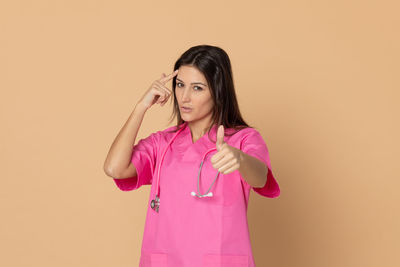 Portrait of woman standing against pink background