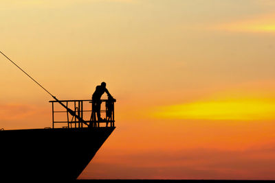 Silhouette man standing by sea against sky during sunset