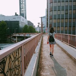 Rear view of woman walking on footpath in city