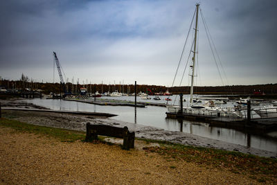 Sailboats moored at harbor against sky