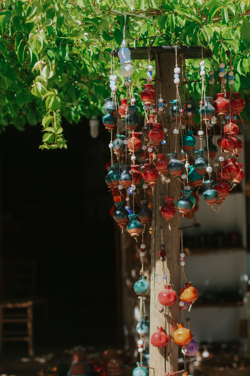 CLOSE-UP OF MULTI COLORED GLASS DECORATION HANGING ON PLANTS