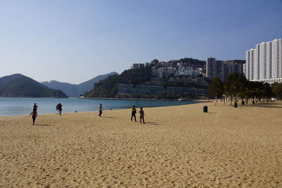 People on beach against clear sky