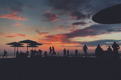 Silhouette people on beach against sky during sunset