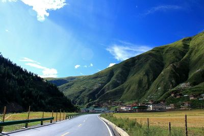 Road amidst mountains against blue sky