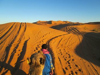 High angle view of man walking with camel on desert