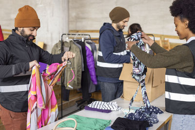 Male and female workers sorting recycled clothes on table at recycling center