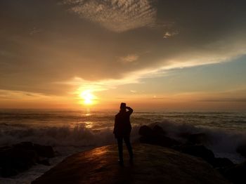 Silhouette of people standing on beach at sunset