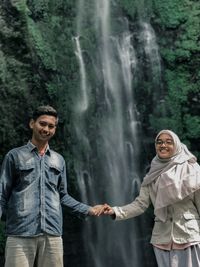 Smiling woman standing with man against waterfall