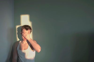 Close-up of young man standing against wall