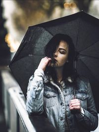 Portrait of young woman with arms outstretched standing against built structure