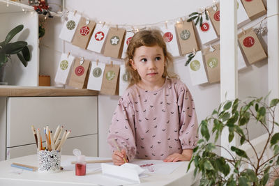 Toddler child writing christmas letter and doing advent calendar tasks in kids room. festive