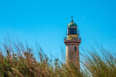 Low angle view of lighthouse by building against clear blue sky