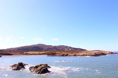 Scenic view of sea and mountains against clear blue sky