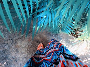 Low section of woman standing by palm leaves