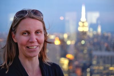 Portrait of smiling mid adult woman in city at dusk