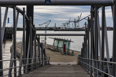 Footbridge leading towards pier over river at commercial dock
