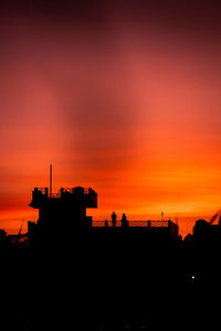 Silhouette buildings against orange sky