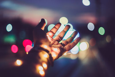 Defocused image of hand holding illuminated lights at night