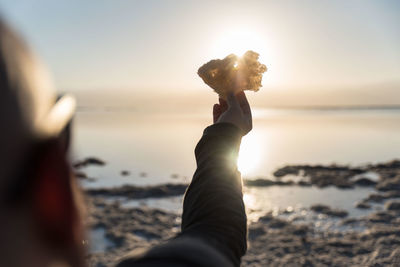 Midsection of woman on beach against sea during sunset