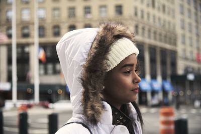Side view of young african american female in outerwear walking along street in new york and enjoying stroll